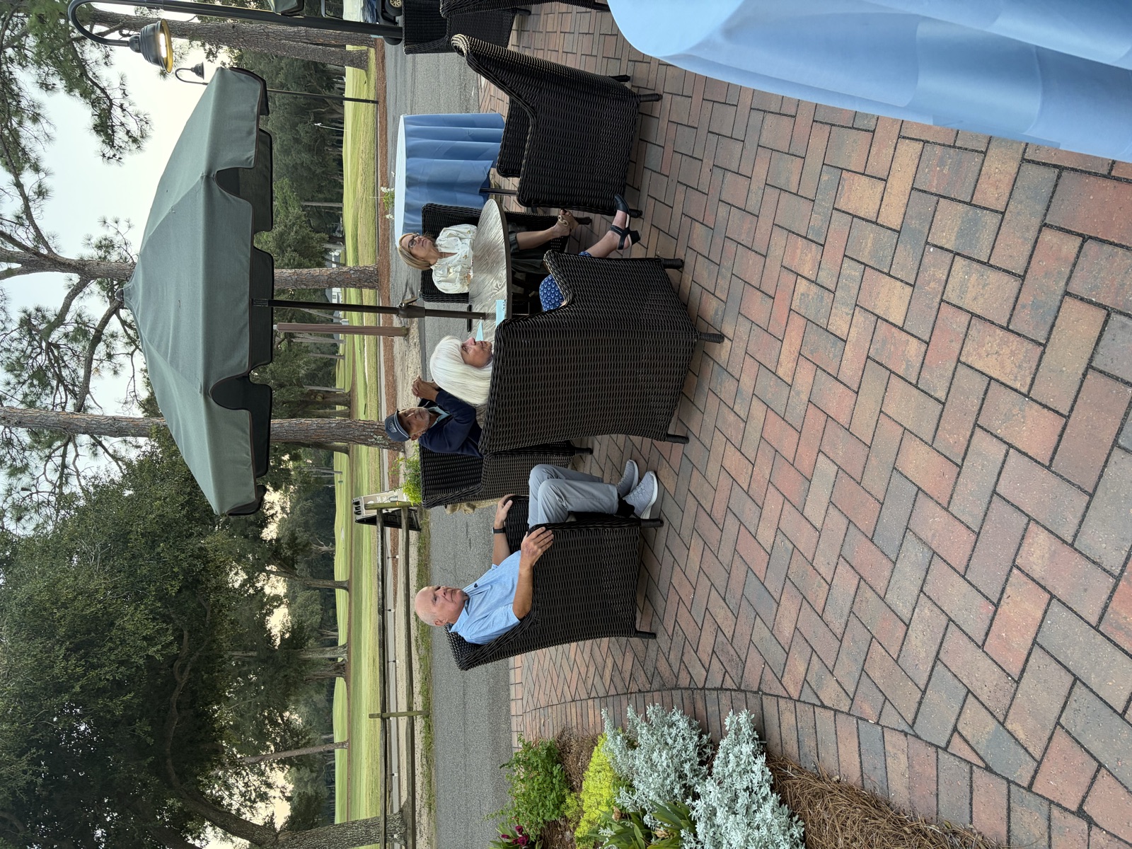 Members sitting in patio chairs beside the course at dusk