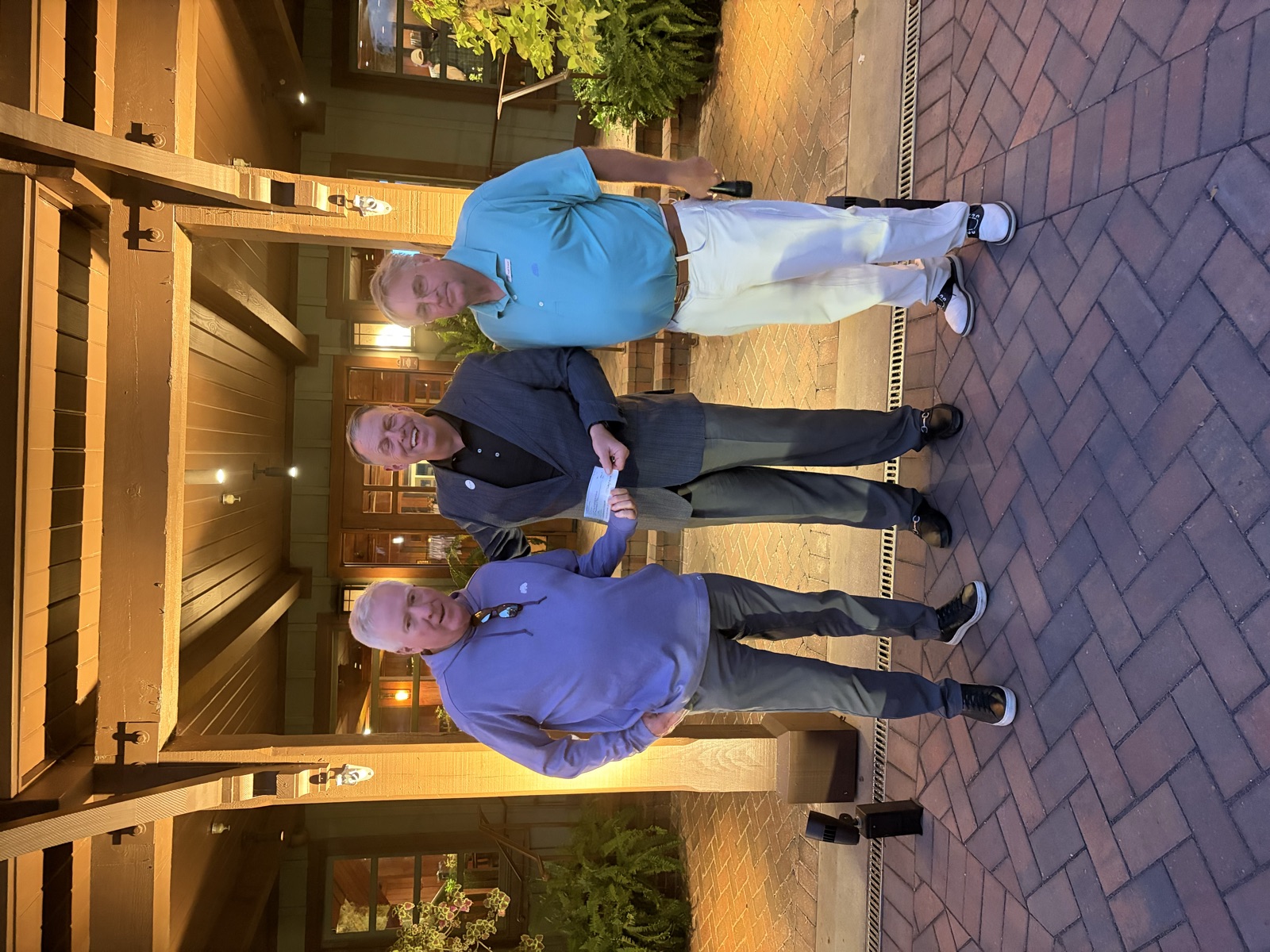 Presenting the tournament’s donation check to The First Tee Gulf Coast on the lit clubhouse portico