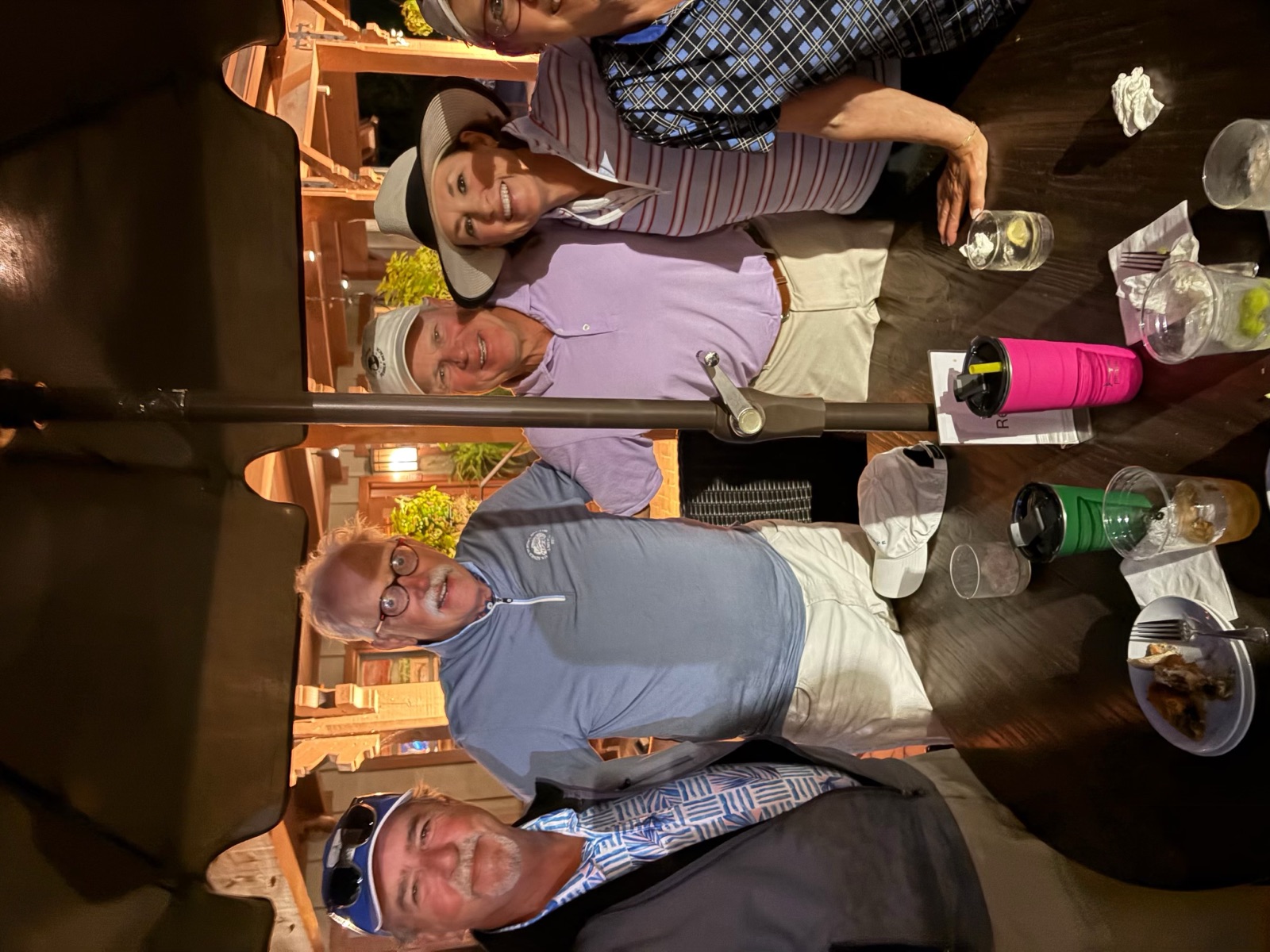 Five people gathered around a patio table under an umbrella after dark